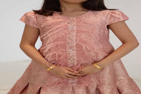 صورة فستان لحمي مع الؤلؤ والريش في نص الفستان